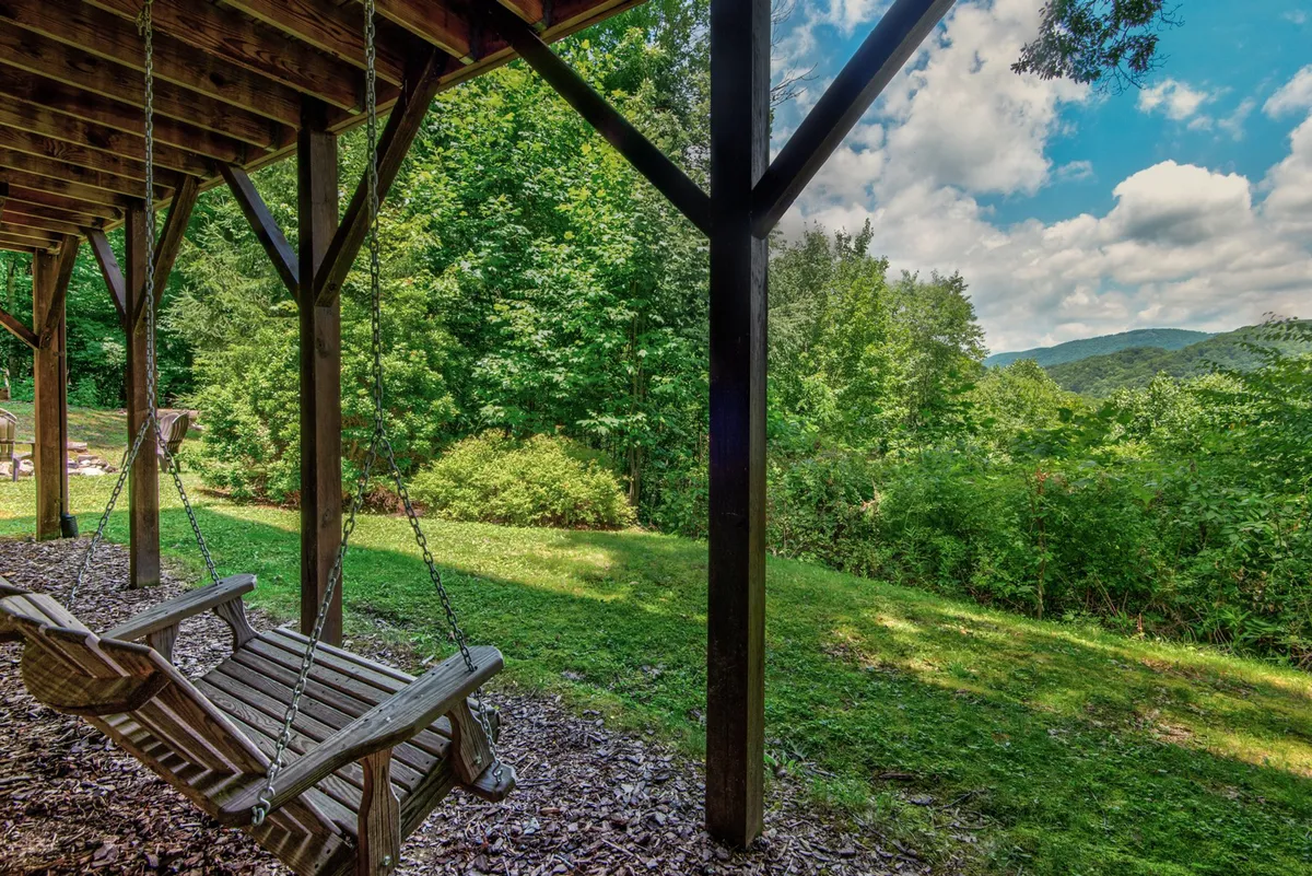 An inviting wooden swing set amidst lush greenery, overlooking a stunning mountain view. The tranquil scene suggests relaxation after an active day.