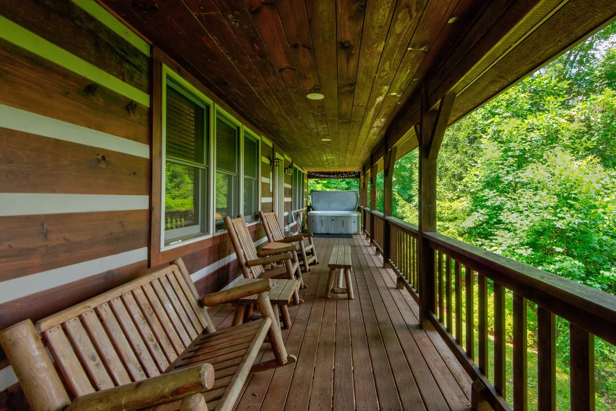 This image features an inviting porch lined with classic wooden rocking chairs and a table, set against a tranquil green landscape. The space is perfectly suited for group relaxation, shared conversations, and enjoying the natural surroundings together.