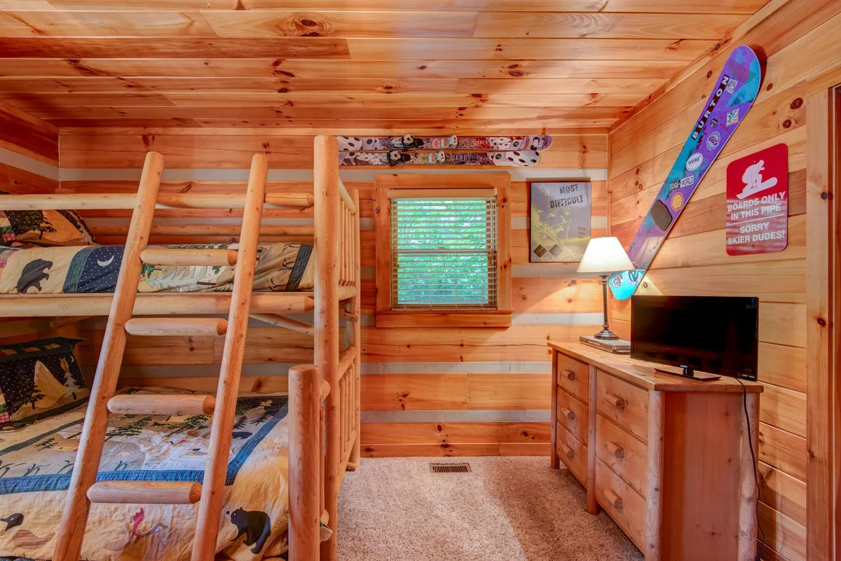 A playful and inviting bedroom with twin-over-full bunk beds, rustic wooden furniture, ski decorations, and a cozy lamp. The setup is perfect for kids or groups of friends, embodying the fun, flexible sleeping arrangements described.