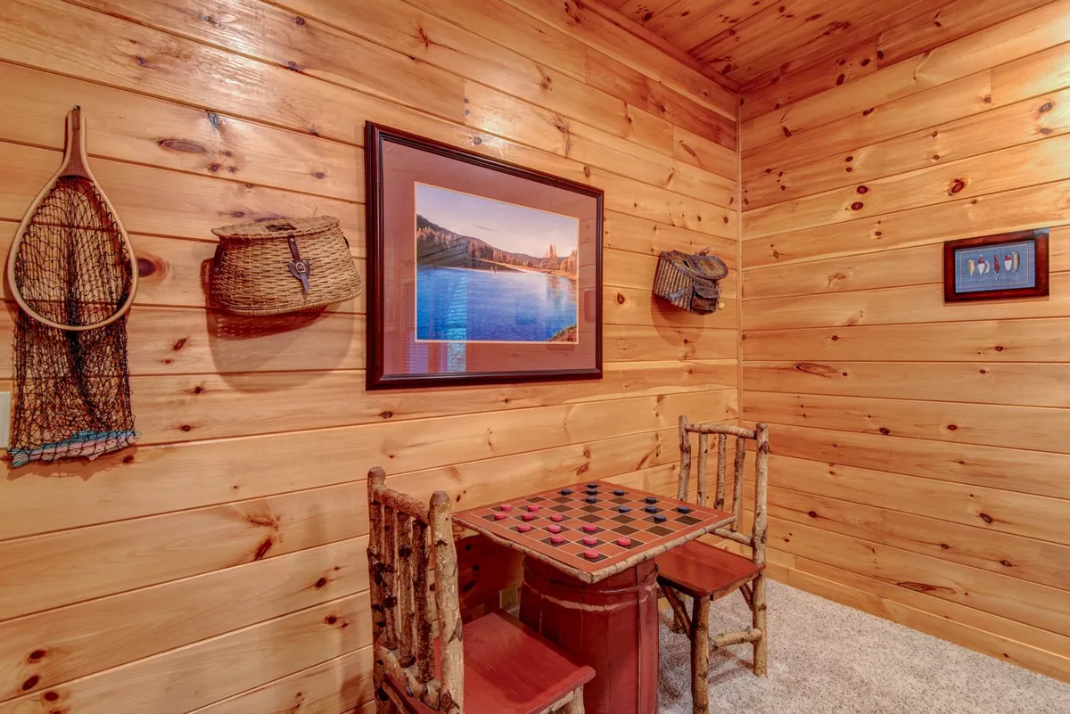 A rustic, charming nook featuring a checkerboard game table, framed artwork, and warm wooden walls. Baskets and rustic chairs create a nostalgic, welcoming mood perfect for board games and intimate conversations.